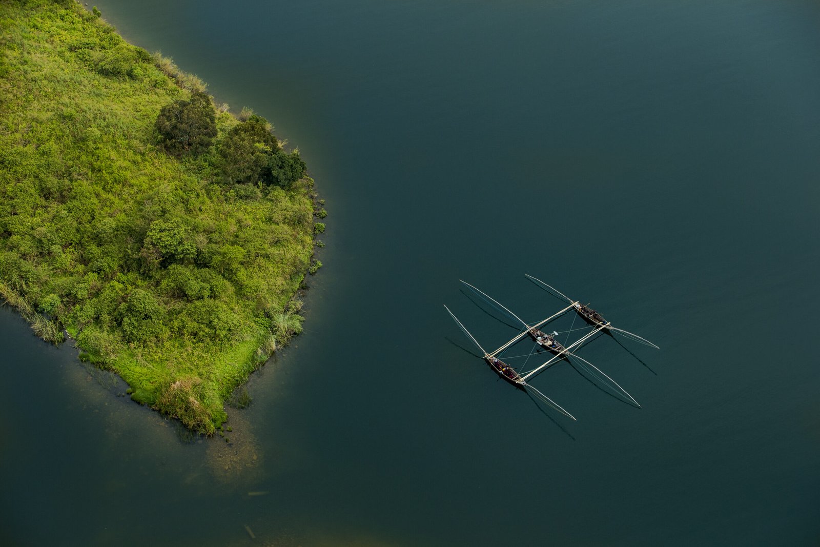 Aerial view of a fishing boat beside a green island on Lake Kivu
